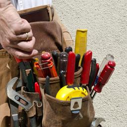 An electrician's tool pouch. It is full of tools including a tape measure, pliers, and screw drivers.