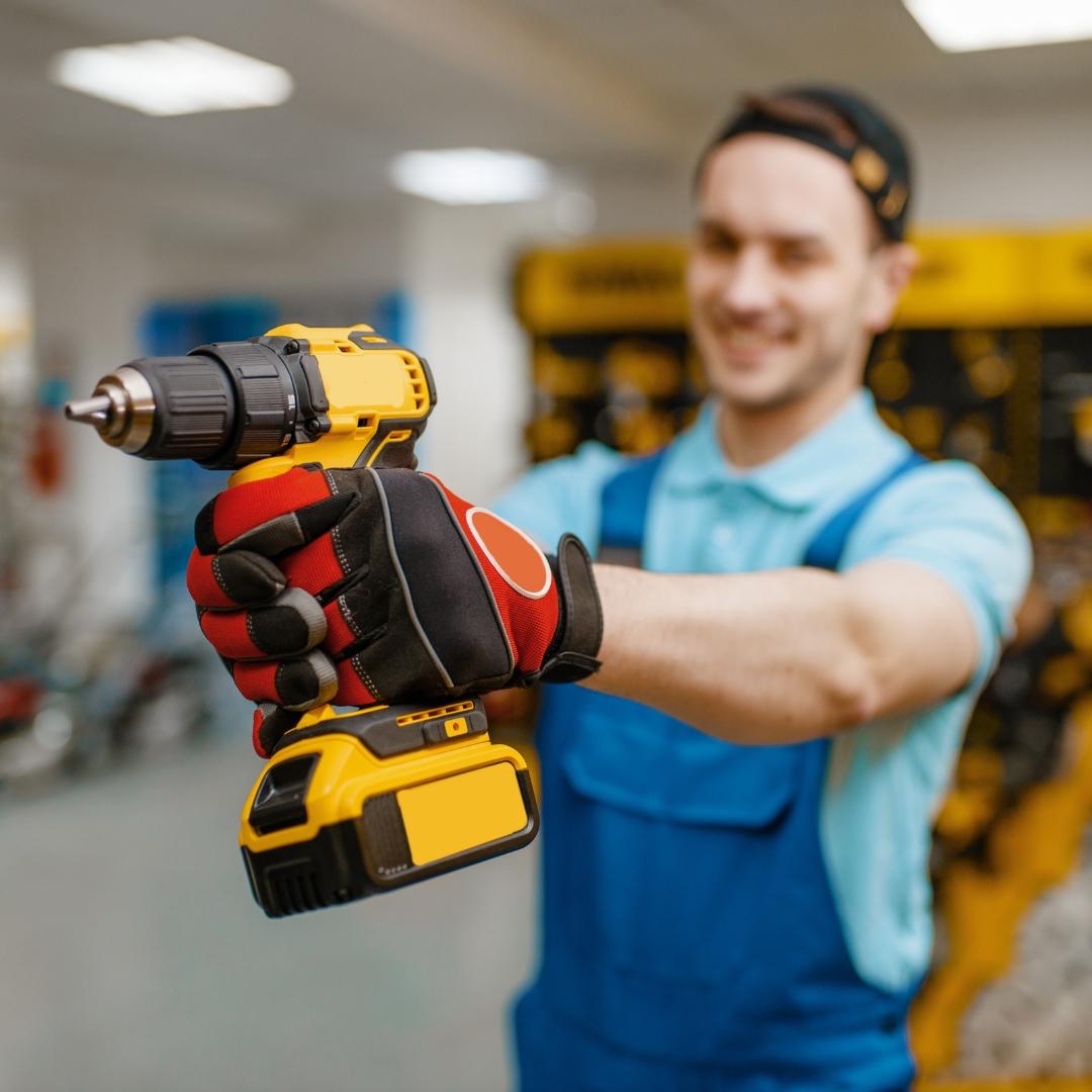 An electrician holding a yellow and black impact driver.